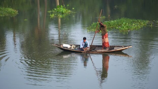 View of fishermen in a wooden boat on a calm river in Bogura Bangladesh.