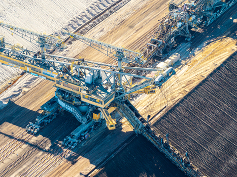Aerial view of the Tagebau Welzow Sud brown coal open pit mine featuring a massive bucket wheel excavator operating on dark soil tracks in Spremberg Brandenburg Germany. Aerial view of the Tagebau Welzow Sud brown coal open pit mine featuring a massive bucket wheel excavator operating on dark soil tracks in Spremberg Brandenburg Germany.