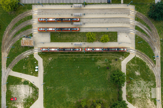 Aerial view of a modern tram depot with red and yellow trams parked on tracks surrounded by green lawns and pedestrian paths in Warszawa Wojewodztwo mazowieckie Poland. Aerial view of a modern tram depot with red and yellow trams parked on tracks surrounded by green lawns and pedestrian paths in Warszawa Wojewodztwo mazowieckie Poland.