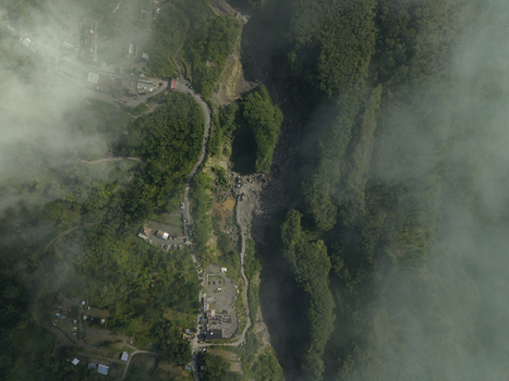 Aerial view of Tambang Pasir Merapi Kali Gendol Sand Mine with a winding road and lush green forests through the mist in Kecamatan Cangkringan Daerah Istimewa Yogya Indonesia. Aerial view of Tambang Pasir Merapi Kali Gendol Sand Mine with a winding road and lush green forests through the mist in Kecamatan Cangkringan Daerah Istimewa Yogya Indonesia.