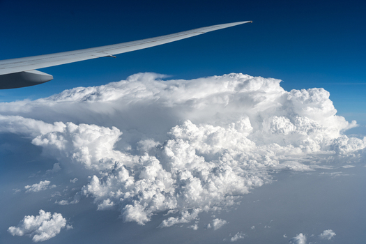 Aerial view of an airplane wing over massive white cumulus clouds and a deep blue sky in India. Aerial view of an airplane wing over massive white cumulus clouds and a deep blue sky in India.