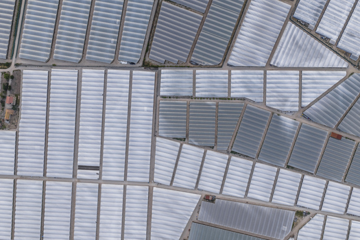 Aerial view of vast greenhouse complexes and agricultural plastic tunnels arranged in geometric patterns in Paestum Campania Italy.
