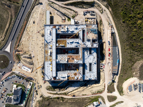 Aerial view of an Hospital large construction site featuring a multi wing building structure with cranes surrounding dirt grounds and nearby road infrastructure in Ancona Marche Italy. Aerial view of an Hospital large construction site featuring a multi wing building structure with cranes surrounding dirt grounds and nearby road infrastructure in Ancona Marche Italy.