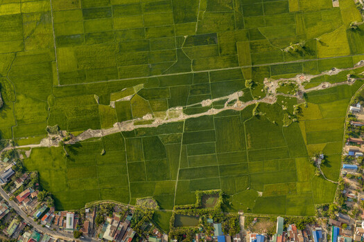 Aerial view of Lak Lake surrounded by vibrant green rice paddies and rural residential areas under warm golden hour light in Lien Son Lak Dak Lak Vietnam. Aerial view of Lak Lake surrounded by vibrant green rice paddies and rural residential areas under warm golden hour light in Lien Son Lak Dak Lak Vietnam.