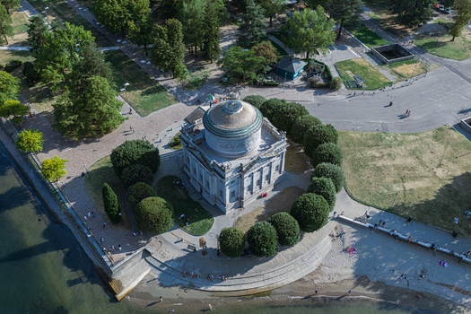 Aerial view of the Tempio Voltiano neoclassical temple surrounded by lush trees and manicured gardens on the shore of Lake Como in Como Lombardy Italy.