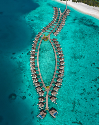 Aerial view of overwater bungalows arranged in a fish shape over turquoise lagoon waters in Kudahuvadhoo Dhaalu Atoll Maldives. Aerial view of overwater bungalows arranged in a fish shape over turquoise lagoon waters in Kudahuvadhoo Dhaalu Atoll Maldives.