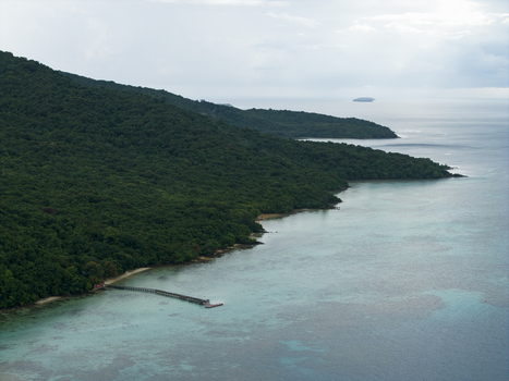 Aerial view of verdant island slopes meet the tranquil turquoise sea a pier stretching into the calm waters at Turtle Conservation Karimunjawa Central Java Indonesia.