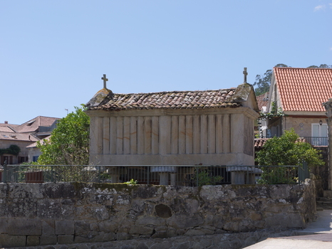 View of a traditional stone horreo granary with a tiled roof and stone pillars in the historic village of Combarro Pontevedra Spain.