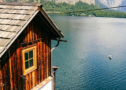 View of a traditional wooden house overlooking the calm waters of Hallstatter See with surrounding mountains in Hallstatt Upper Austria Austria. View of a traditional wooden house overlooking the calm waters of Hallstatter See with surrounding mountains in Hallstatt Upper Austria Austria.