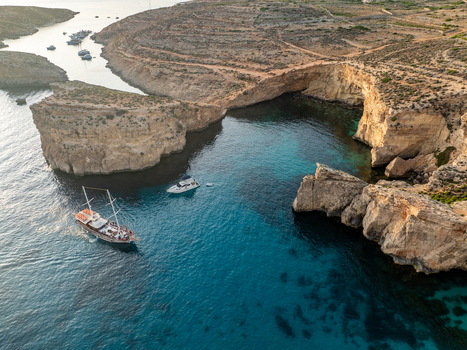 Aerial view of boats sailing through the turquoise waters contrasting with the rugged sun kissed cliffs of the Blue Lagoon Comino Malta. Aerial view of boats sailing through the turquoise waters contrasting with the rugged sun kissed cliffs of the Blue Lagoon Comino Malta.