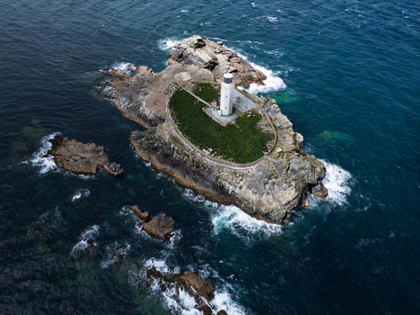 Aerial view of Godrevy Lighthouse on a rocky island surrounded by the dark blue waters of the Atlantic Ocean in Gwithian England United Kingdom. Aerial view of Godrevy Lighthouse on a rocky island surrounded by the dark blue waters of the Atlantic Ocean in Gwithian England United Kingdom.