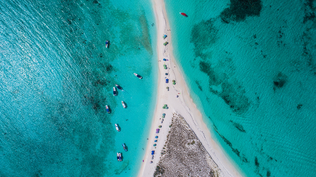 Aerial view of the Los Roques archipelago sandbar surrounded by turquoise waters with anchored boats and people on the white sand beach in Los Roques Dependencias Federale Venezuela. Aerial view of the Los Roques archipelago sandbar surrounded by turquoise waters with anchored boats and people on the white sand beach in Los Roques Dependencias Federale Venezuela.
