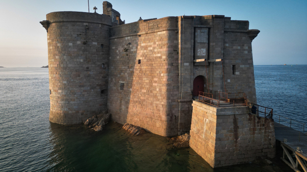 Aerial view of the imposing Ch&acirc;teau du Taureau fortress rises from the sea its weathered stone reflecting the golden light of the setting sun Plouezoc h Bretagne France.