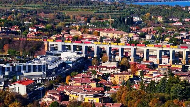 Aerial view of a train crossing a concrete viaduct in Italy.