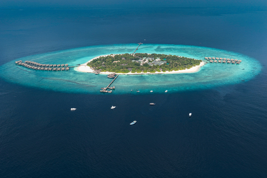 Aerial view of a tropical island resort with overwater bungalows lush vegetation and turquoise coral reefs surrounded by deep blue ocean water Hoarafushi Haa Alif Atoll Maldives. Aerial view of a tropical island resort with overwater bungalows lush vegetation and turquoise coral reefs surrounded by deep blue ocean water Hoarafushi Haa Alif Atoll Maldives.