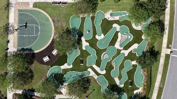 Aerial view of a miniature golf course and an adjacent basketball court surrounded by trees and residential landscaping in St. Johns County Florida United States. Aerial view of a miniature golf course and an adjacent basketball court surrounded by trees and residential landscaping in St. Johns County Florida United States.