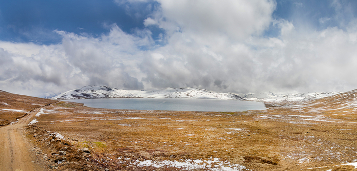 View of Shausar Lake surrounded by snow capped mountains and brown rocky terrain under a cloudy sky in Skardu Gilgit Pakistan. View of Shausar Lake surrounded by snow capped mountains and brown rocky terrain under a cloudy sky in Skardu Gilgit Pakistan.