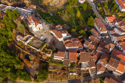 Aerial view of the historic village of Coja featuring the parish church and traditional terracotta rooftops surrounded by lush greenery in Coja Coimbra District Portugal. Aerial view of the historic village of Coja featuring the parish church and traditional terracotta rooftops surrounded by lush greenery in Coja Coimbra District Portugal.