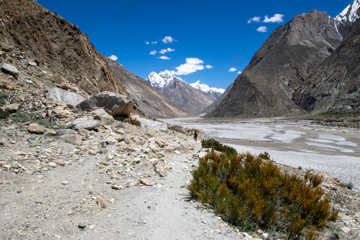 View of K2 Base Camp featuring rugged rocky terrain sparse vegetation and snow capped mountain peaks under a clear blue sky in Gilgit Pakistan. View of K2 Base Camp featuring rugged rocky terrain sparse vegetation and snow capped mountain peaks under a clear blue sky in Gilgit Pakistan.