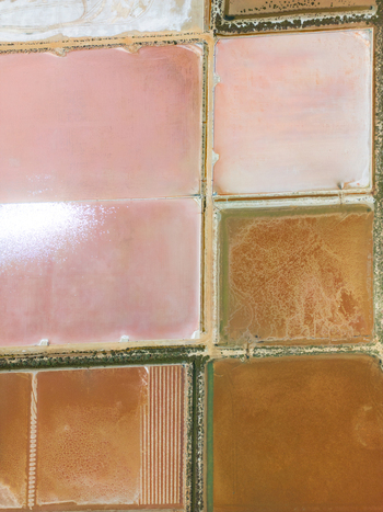 Aerial view of Salines des Trenc salt evaporation ponds with vibrant pink and brown water under bright sunlight in Campos Islas Baleares Spain. Aerial view of Salines des Trenc salt evaporation ponds with vibrant pink and brown water under bright sunlight in Campos Islas Baleares Spain.