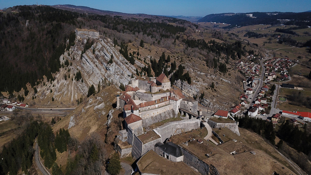 Aerial view of the historic fortress of Chateau de Joux perched on a rocky cliff overlooking the village and surrounding valley in La Cluse et Mijoux Bourgogne Franche Com France. Aerial view of the historic fortress of Chateau de Joux perched on a rocky cliff overlooking the village and surrounding valley in La Cluse et Mijoux Bourgogne Franche Com France.