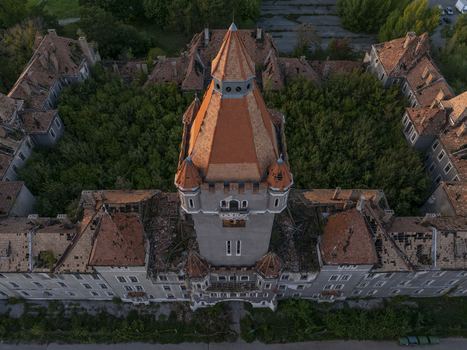 Aerial view of the abandoned Hajmasker Barracks with its prominent central tower decaying red tile roofs and an overgrown courtyard in Hajmasker Hungary. Aerial view of the abandoned Hajmasker Barracks with its prominent central tower decaying red tile roofs and an overgrown courtyard in Hajmasker Hungary.