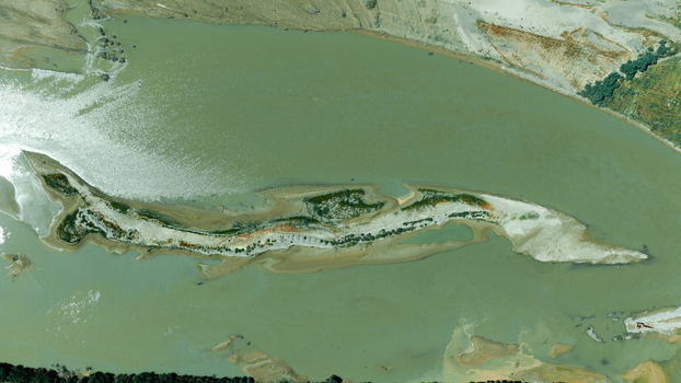 Aerial view of a long narrow sandbar island in the middle of a river with murky green water and sparse vegetation in Miqdadiyah Diyala Governorate Iraq.