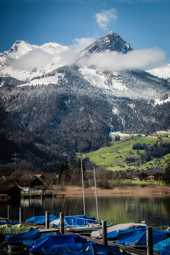View of serene waters reflecting the snow capped mountains set against lush green hillsides creating a picturesque scene Train from Lucerne to Interlaken Switzerland. View of serene waters reflecting the snow capped mountains set against lush green hillsides creating a picturesque scene Train from Lucerne to Interlaken Switzerland.