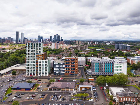Aerial view of MediaCityUK featuring modern residential apartment buildings urban streets and a distant city skyline under a cloudy sky in Salford England United Kingdom. Aerial view of MediaCityUK featuring modern residential apartment buildings urban streets and a distant city skyline under a cloudy sky in Salford England United Kingdom.