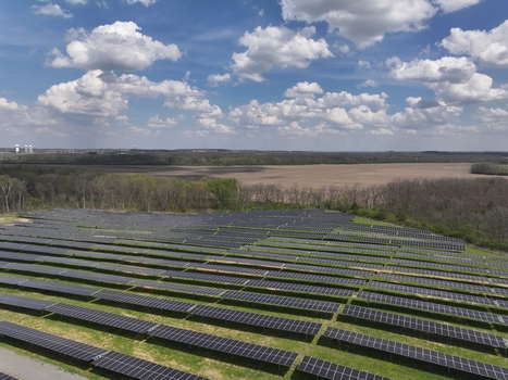 Lebanon United States 12 April 2026 Aerial view of a large solar farm with rows of photovoltaic panels surrounded by green trees and open fields under a blue sky with white clouds.