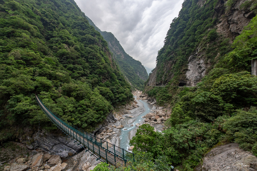 View of the suspension bridge spanning the Liwu River in Taroko National Park surrounded by steep forested gorge walls and rocky terrain in Xiulin Township Hualien County Taiwan.