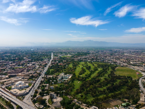 Aerial view of Bala Hisar Fort and the surrounding cityscape featuring a green golf course urban buildings and distant mountains in Peshawar Khyber Pakhtunkhwa Pakistan.