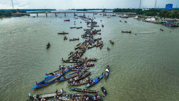 Baghabari Rajshahi Division Bangladesh 20 August 2022 Aerial view of Baghabari river filled with numerous wooden boats and people with a bridge spanning the water.