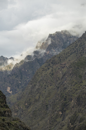 View of steep rocky mountain slopes partially covered in mist and low clouds under an overcast sky Chilas Gilgit Pakistan. View of steep rocky mountain slopes partially covered in mist and low clouds under an overcast sky Chilas Gilgit Pakistan.