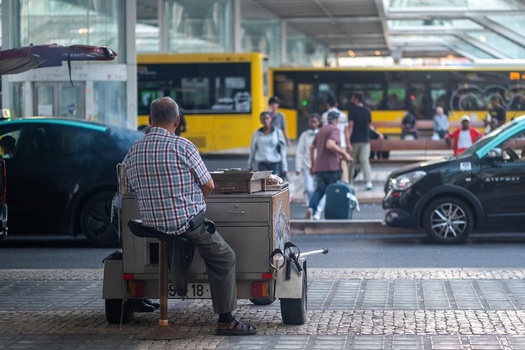 Lisboa Portugal 19 September 2026 View of a man sitting at a mobile food cart at the Gare do Oriente transport hub with buses and commuters in the background. Lisboa Portugal 19 September 2026 View of a man sitting at a mobile food cart at the Gare do Oriente transport hub with buses and commuters in the background.