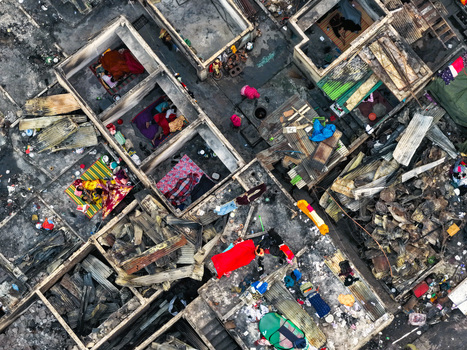 Aerial view of Korail Basti showing dense housing structures with remnants of fire colorful blankets and people in small living spaces in Dhaka Dhaka Division Bangladesh.