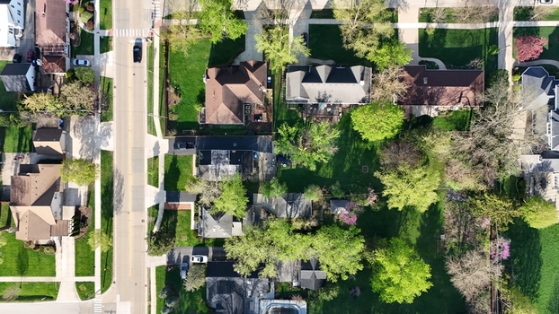 Aerial view of a residential neighborhood featuring houses lush green lawns and blooming trees along a quiet street Chicago Illinois United States. Aerial view of a residential neighborhood featuring houses lush green lawns and blooming trees along a quiet street Chicago Illinois United States.