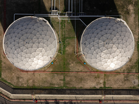 Aerial view of two large circular industrial storage tanks with geodesic dome roofs connected by piping in an industrial facility in Bajos de Haina San Cristobal Province Dominican Republic.