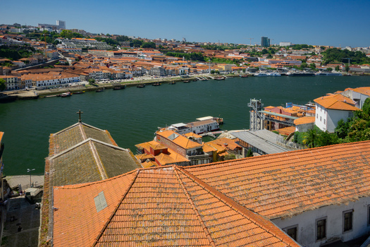 Aerial view of terracotta rooftops cascading towards the shimmering Douro River reflecting the clear blue sky Porto Porto District Portugal. Aerial view of terracotta rooftops cascading towards the shimmering Douro River reflecting the clear blue sky Porto Porto District Portugal.