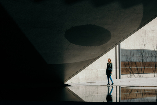 Zurich Switzerland 02 April 2023 View of a solitary figure stands in stark contrast against the geometric shadows and bright light of the National Museum Zurich reflected in a shallow pool. Zurich Switzerland 02 April 2023 View of a solitary figure stands in stark contrast against the geometric shadows and bright light of the National Museum Zurich reflected in a shallow pool.