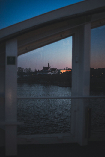 View of the Port of Helsinki and historic waterfront buildings across the water at twilight seen through a white window frame Helsinki Uusimaa Finland. View of the Port of Helsinki and historic waterfront buildings across the water at twilight seen through a white window frame Helsinki Uusimaa Finland.
