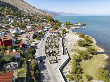 Aerial view of the lakeside village of Shiroke featuring residential houses a parking area and the scenic Lake Shkodra in Shiroke Qarku i Shkodres Albania. Aerial view of the lakeside village of Shiroke featuring residential houses a parking area and the scenic Lake Shkodra in Shiroke Qarku i Shkodres Albania.