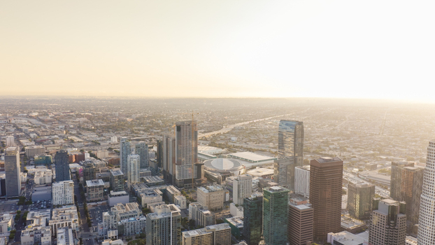 Aerial view of the Los Angeles skyline with modern skyscrapers dense urban architecture and city streets bathed in golden hour light Los Angeles California United States.