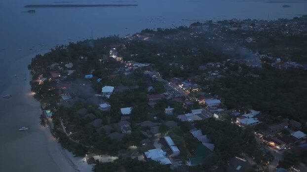 Aerial view of Siargao Island at dusk with town lights Philippines.