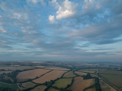 Aerial view of agricultural farmland with harvested fields hedgerows and rural tracks under a cloudy sky in Looe Cornwall United Kingdom. Aerial view of agricultural farmland with harvested fields hedgerows and rural tracks under a cloudy sky in Looe Cornwall United Kingdom.