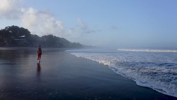 Aerial view of a woman walking on a misty beach in Bali Indonesia. Aerial view of a woman walking on a misty beach in Bali Indonesia.