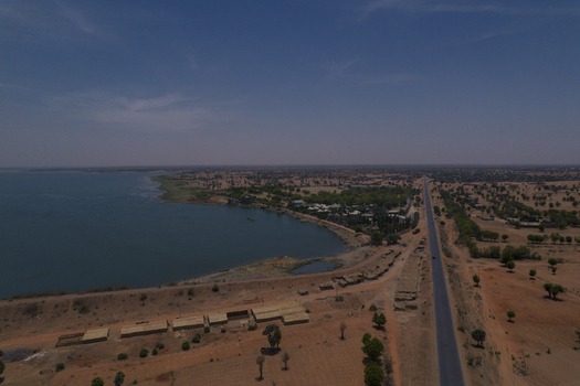 Aerial view of the Minjibir reservoir and surrounding arid landscape with a straight road and scattered vegetation in Kano Kano State Nigeria. Aerial view of the Minjibir reservoir and surrounding arid landscape with a straight road and scattered vegetation in Kano Kano State Nigeria.