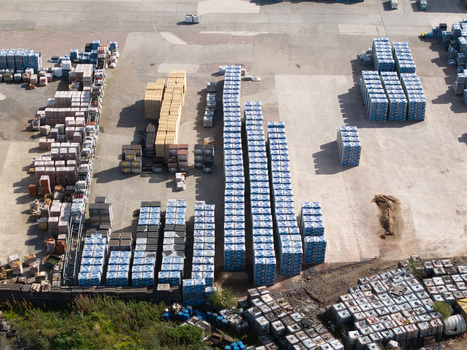 Aerial view of a large industrial storage yard filled with neatly stacked pallets of construction materials and blue wrapped goods in Lisburn Northern Ireland United Kingdom. Aerial view of a large industrial storage yard filled with neatly stacked pallets of construction materials and blue wrapped goods in Lisburn Northern Ireland United Kingdom.