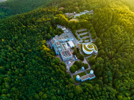 Aerial view of the Max Planck Institute for Astronomy in a forest with modern buildings a spiral structure and observatory domes in golden light Heidelberg Baden Wurttemberg Germany.