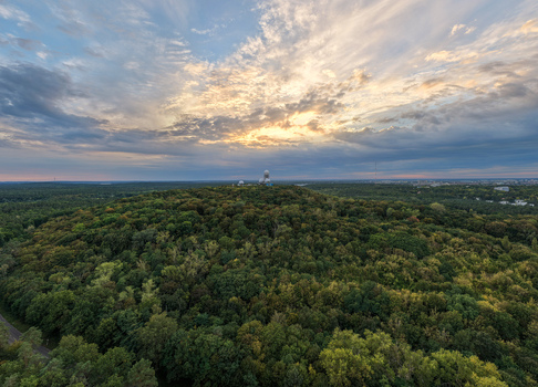 Aerial view of Teufelsberg NSA Station with its iconic radar domes set atop a forested hill under a dramatic sunset sky in Berlin Berlin Germany.